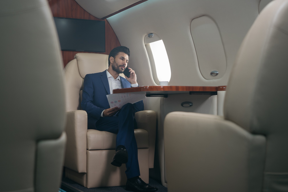 middle-eastern-businessman-talking-mobile-phone-holding-financial-reportflying-private-jet